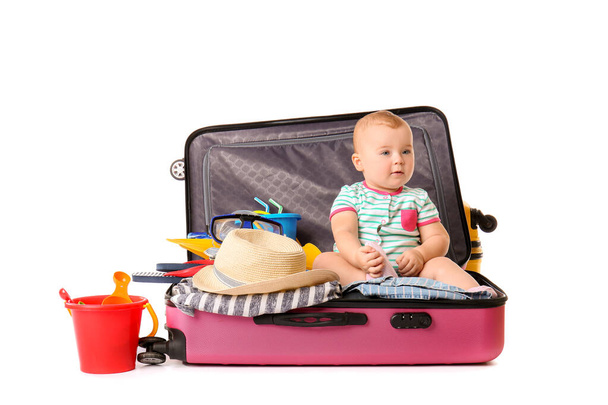 niedliches Baby mit Koffer und Habseligkeiten auf weißem Hintergrund - Foto, Bild