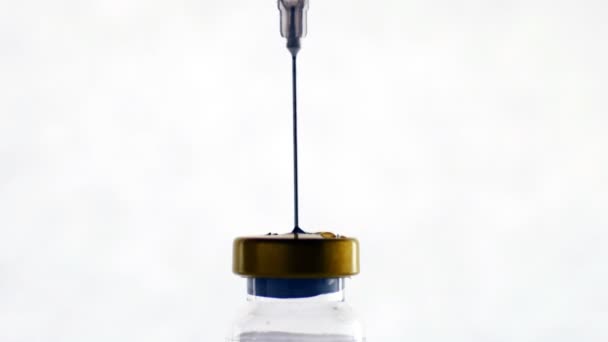 Κοντινό πλάνο σύριγγας γεμισμένης με υγρό από ένα μπουκάλι γυαλί - Πλάνα, βίντεο
