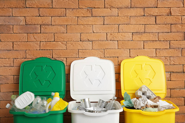Contenedores con diferentes tipos de basura cerca de la pared de ladrillo. Concepto de reciclaje
 - Foto, Imagen