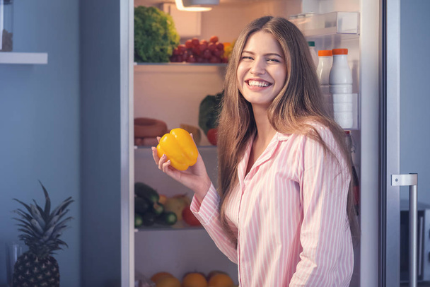 schöne junge Frau bei der Wahl von Lebensmitteln im Kühlschrank nachts - Foto, Bild