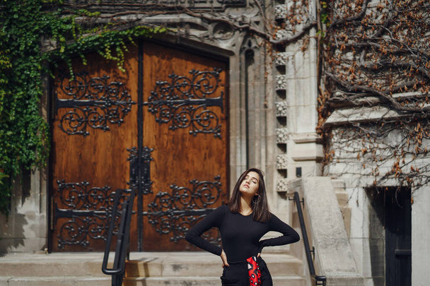 stylish brunette standing next to the entance to a building - Foto, afbeelding