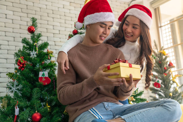 Beautiful Asian girl give surprise Christmas gift to her boyfriend in Christmas holiday season greeting. - Фото, зображення