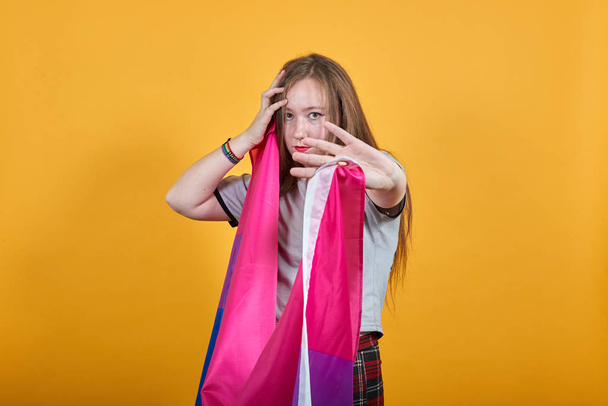 Portrait of young woman showing stop gesture keeping bisexual flag - Photo, image