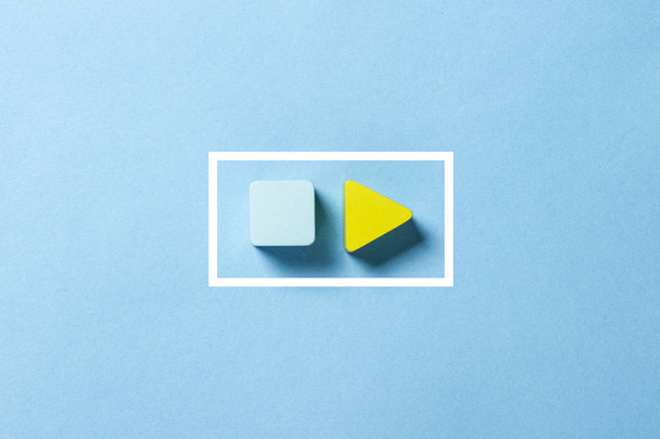 Yellow triangle on a blue background. Play sign. Minimalism. Flat lay, top view - Photo, Image