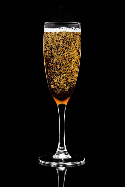 A single champagne glass filled with golden bright sparkling wine with foam and bubbles isolated on a black background. Design element, clipping path. - Fotografie, Obrázek