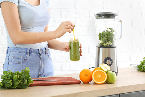 Woman with healthy homemade smoothie in kitchen - Foto, Bild