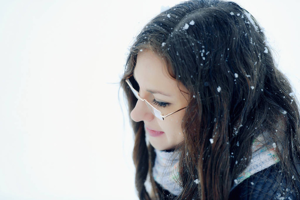 Portret van een meisje in de winter outdoor close-up. Romantisch meisje met bril voor zicht op straat in de winter onder de sneeuw. Mooie jonge brunette vrouw in de winter landschap - Foto, afbeelding