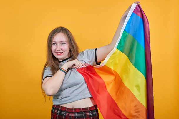 Retrato de una atractiva joven mujer mirando la cámara, empujando la bandera LGBT
 - Foto, imagen