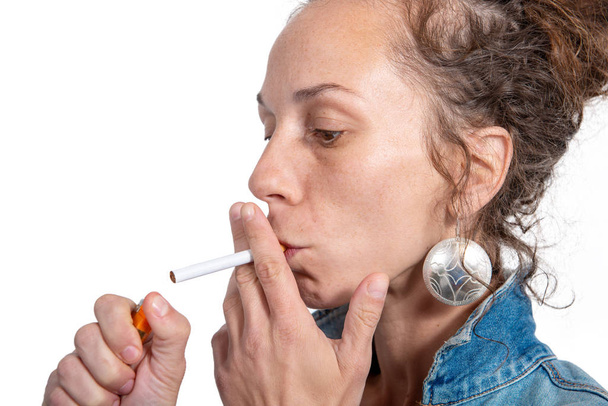 junge Frau zündet sich Zigarette auf weißem Hintergrund an - Foto, Bild