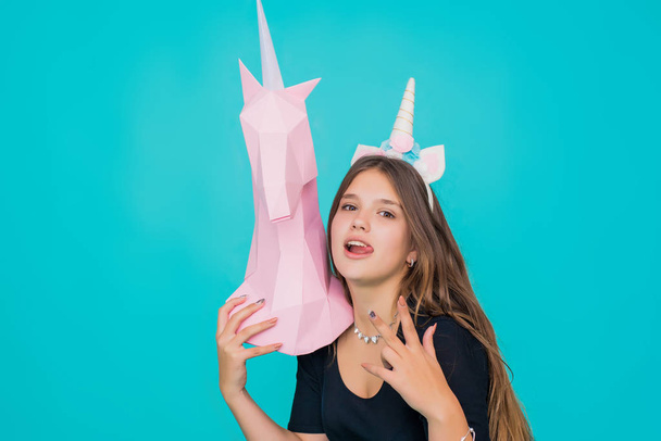 Adolescente Kawaii. Jeune femme mignonne avec corne de licorne tenant à la main papier rose licorne sur fond bleu
. - Photo, image