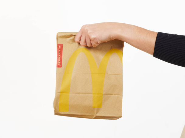 GOMEL, BELARUS NOVEMBER 18, 2019: girl holds a packet of food from McDonald's on a white background. - 写真・画像