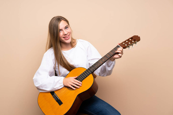 Teenager girl with guitar over isolated background - Фото, изображение