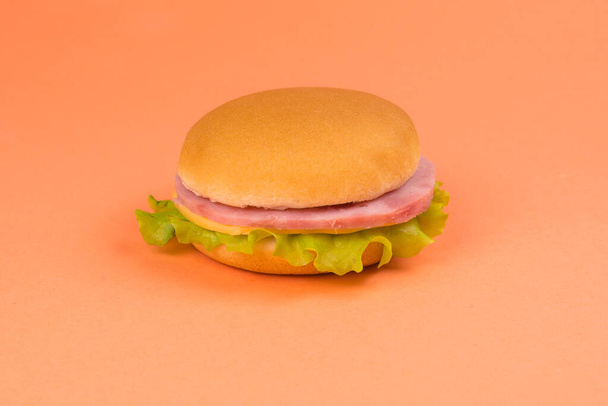 Sandwich with ham, cheese, lettuce on orange background. - Fotó, kép