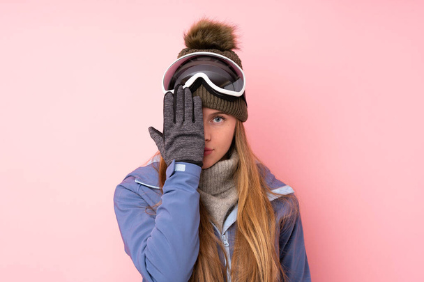 Síléc tinédzser lány snowboard szemüveg felett elszigetelt rózsaszín háttér amely egy szem kézzel - Fotó, kép