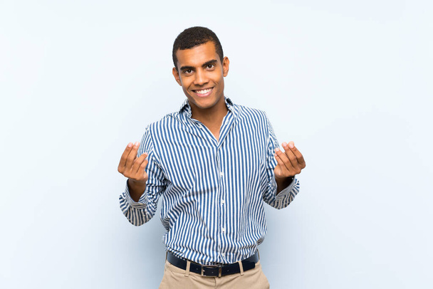 Young handsome brunette man over isolated blue background making money gesture - Φωτογραφία, εικόνα