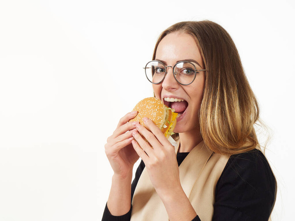 κορίτσι τρώει ένα burger σε λευκό φόντο - Φωτογραφία, εικόνα
