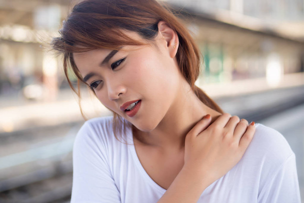женщина с болью в плече или шее; портрет азиатской женщины, страдающей от боли в плече или шее, жесткости, травмы, хронической кости или мышечной травмы; модель здоровья азиатской молодой взрослой женщины
 - Фото, изображение
