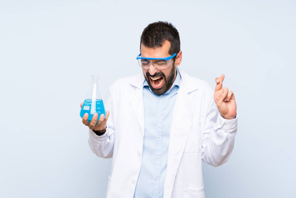 Молодая научная лаборатория держит колбу на изолированном фоне с скрещиванием пальцев
 - Фото, изображение