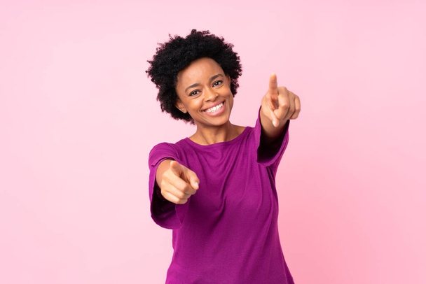 Afrikanische Amerikanerin über isoliertem rosa Hintergrund zeigt lächelnd mit dem Finger auf dich - Foto, Bild