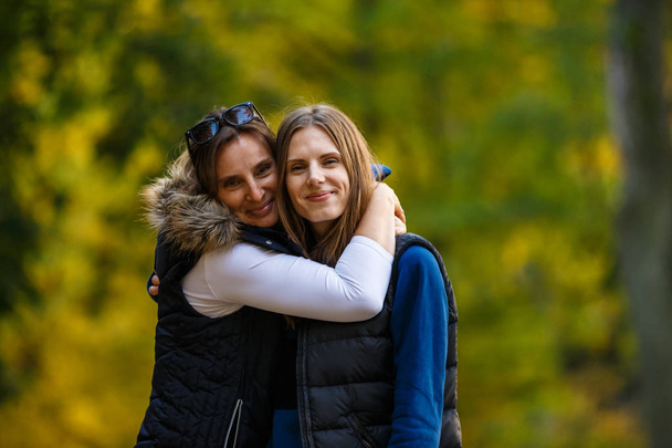 Mother and daughter walking together in autumnal park - Foto, imagen