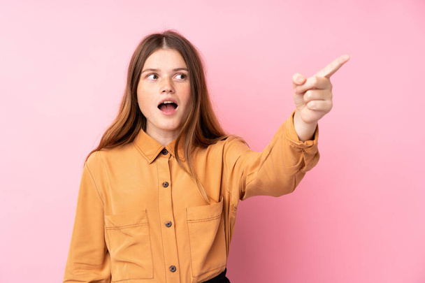 Ukrainian teenager girl over isolated pink background pointing away - Photo, Image