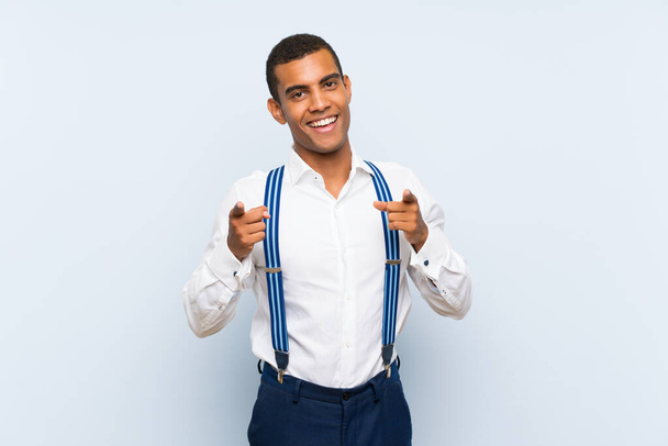 Young handsome brunette man with suspenders over isolated background points finger at you - Zdjęcie, obraz