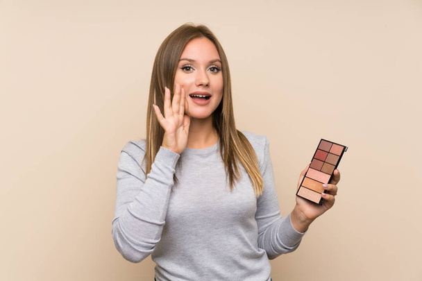 Teenager dívka s make-up paleta přes izolované pozadí křičí s ústy široce otevřené - Fotografie, Obrázek