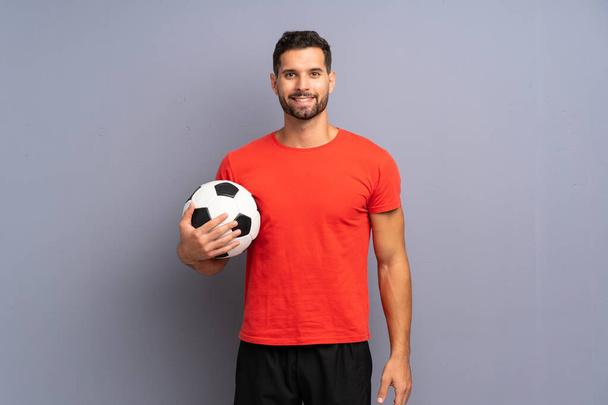 Bonito jovem jogador de futebol homem sobre isolado parede branca sorrindo muito
 - Foto, Imagem