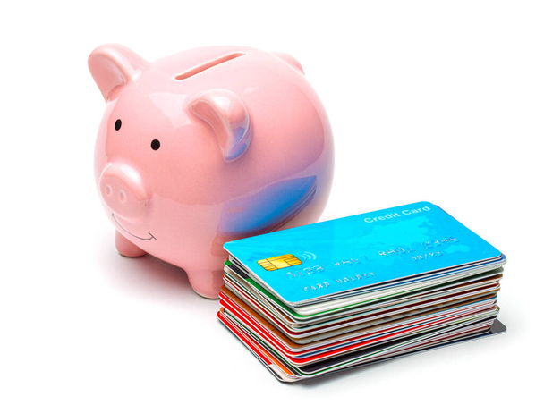 Hucha rosa y tarjetas de crédito en una pila aislada sobre fondo blanco. Cómo ahorrar dinero en una tarjeta de crédito
. - Foto, imagen