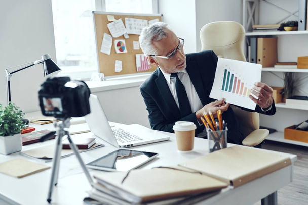 Senior man in elegant business suit showing chart while making social media video - Фото, изображение