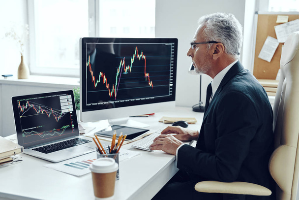 Senior trader in elegant business suit using computer while working at the office - Foto, Imagem