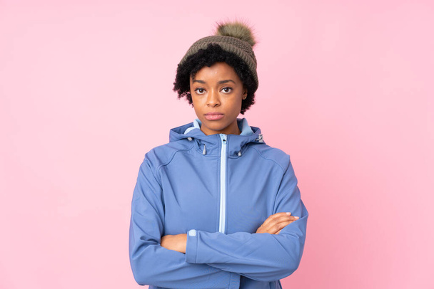 African american woman with winter hat over isolated pink background keeping arms crossed - Photo, Image