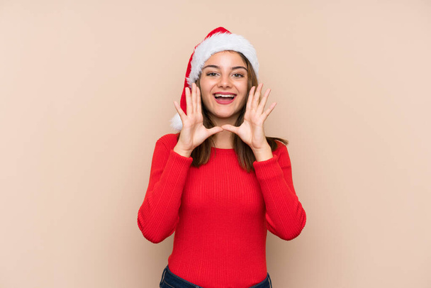 Młoda dziewczyna w świątecznym kapeluszu na odosobnionym tle krzyczy z szeroko otwartymi ustami - Zdjęcie, obraz