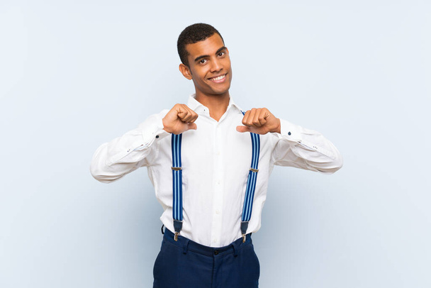 Young handsome brunette man with suspenders over isolated background proud and self-satisfied - Foto, Imagem