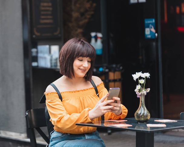 Gyönyörű lány használ okos telefont egy kávézóban. - Fotó, kép