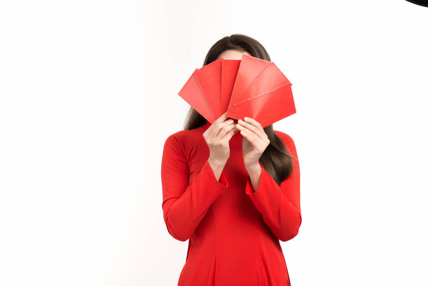 Csinos ázsiai nő piros Ao Dai-t visel és piros borítékot tart a holdújév alkalmából.. - Fotó, kép