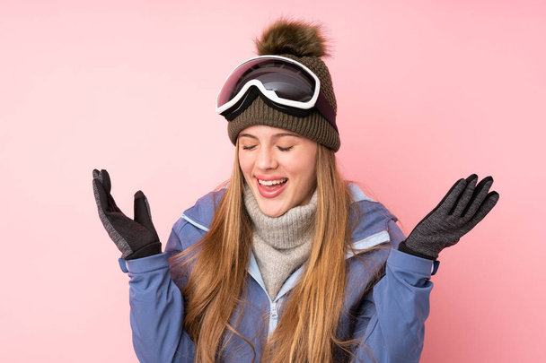 Κορίτσι σκιέρ έφηβος με γυαλιά snowboarding πάνω από απομονωμένο ροζ φόντο γέλιο - Φωτογραφία, εικόνα