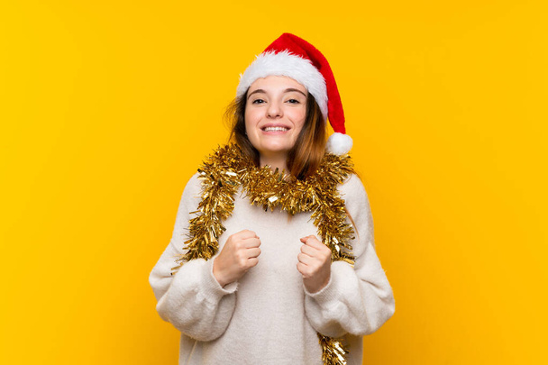 Lány karácsonyi kalap felett elszigetelt sárga háttér ünnepli a győzelem - Fotó, kép