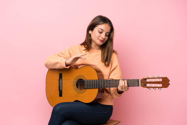 Jeune fille brune avec guitare sur fond rose isolé
 - Photo, image