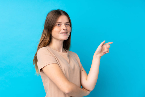 ucraniano adolescente chica sobre aislado azul fondo apuntando dedo a un lado
 - Foto, imagen