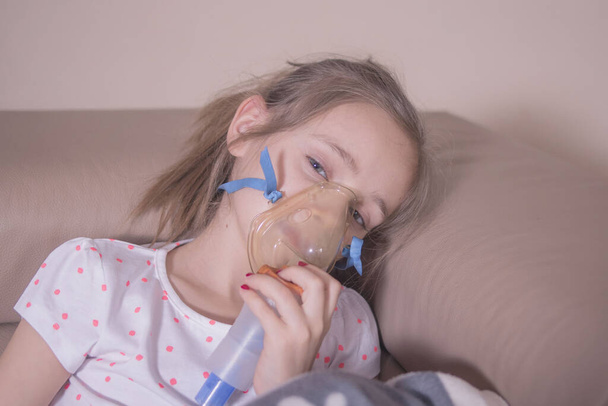 Het kleine meisje inhaleert thuis. Het meisje is ziek, wordt behandeld met inhalatie. - Foto, afbeelding