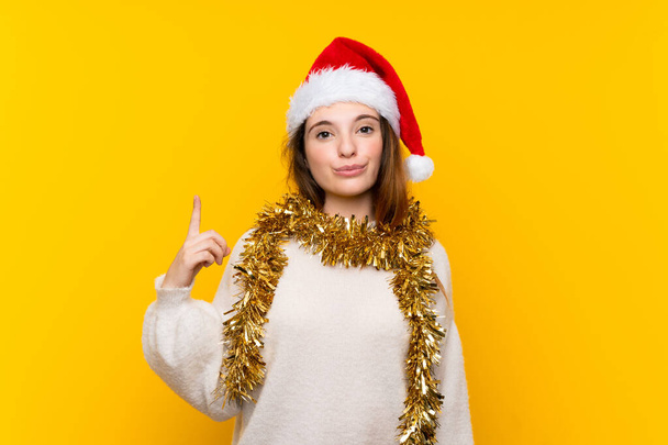 Дівчина з різдвяним капелюхом над ізольованим жовтим тлом, що вказує на індексний палець чудова ідея
 - Фото, зображення