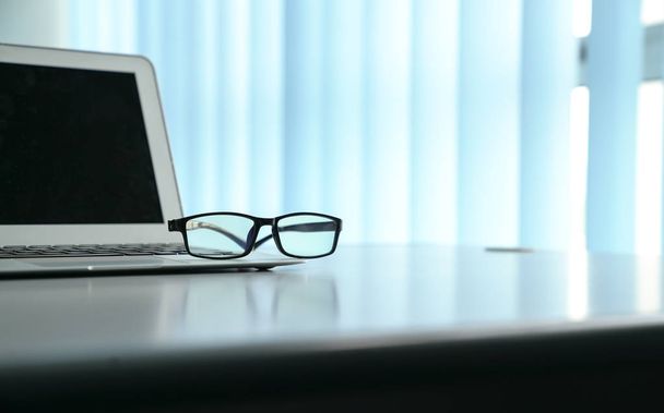 Office table with notebook laptop and reading glasses. Copy spac - Photo, image