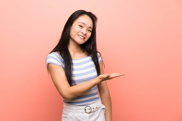 nastolatek Azji dziewczyna na odizolowany różowy tło przedstawiając a idea a patrząc uśmiechnięty w kierunku - Zdjęcie, obraz