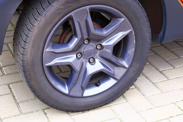 Car wheel, close up. Auto is parked in its parking spot in city. - Photo, Image