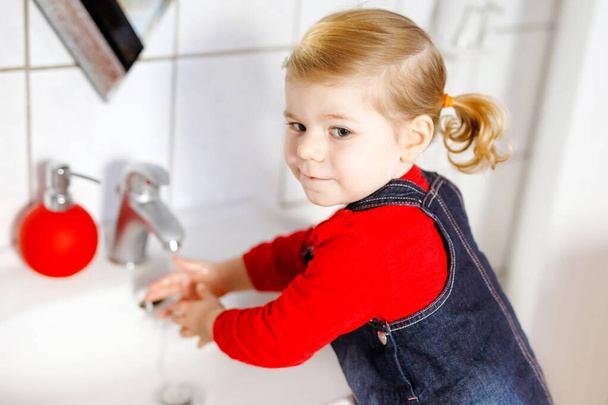 Aranyos kislány kezet mos szappannal és vízzel a fürdőszobában. Imádnivaló gyermek tanulás tisztító testrészek. Reggeli higiéniai rutin. Boldog egészséges gyereket otthon vagy gyerekszobában. - Fotó, kép