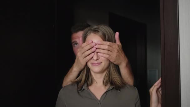 Mann schließt die Augen seiner Frau mit Handflächen und sie betreten eine neue Wohnung - Filmmaterial, Video