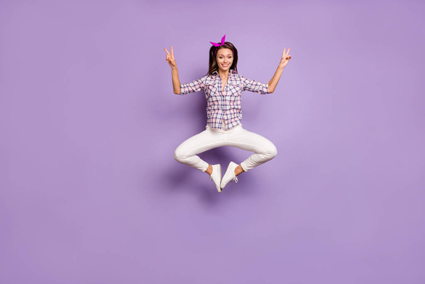 Full body photo of funky girl have spring free time jump make v-sign feel content wear checkered vintage style outfit sneakers isolated over violet color background - Foto, Imagen