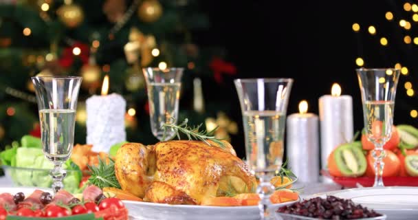 Pörkölt csirke készen áll a karácsonyi ünnepi asztalra pezsgővel közel karácsonyfa és gyertyák. 4k - Felvétel, videó