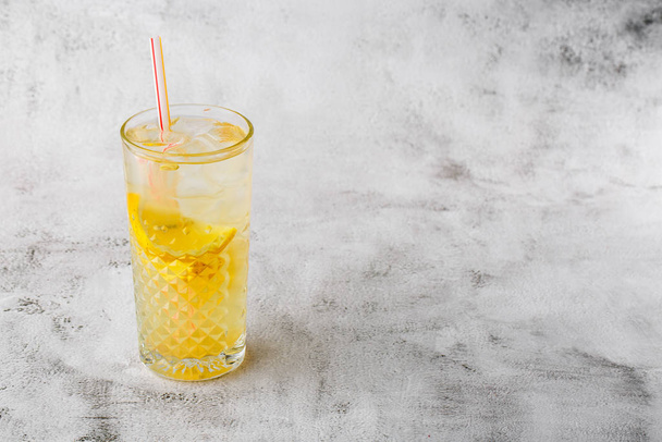 Glass with lemonade with lemon, cold refreshing drink or beverage with ice on bright marble background. Overhead view, copy space. Advertising for cafe menu. Horizontal photo. - Foto, Imagem